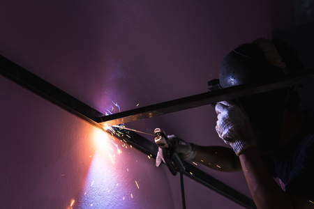 close up worker welding metal with blue arc sparkの写真素材