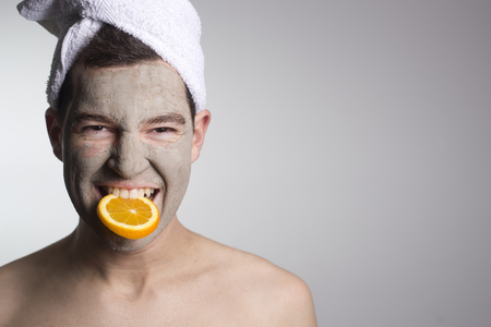 man with a brown mud mask on this face and orange, copy spacedの写真素材
