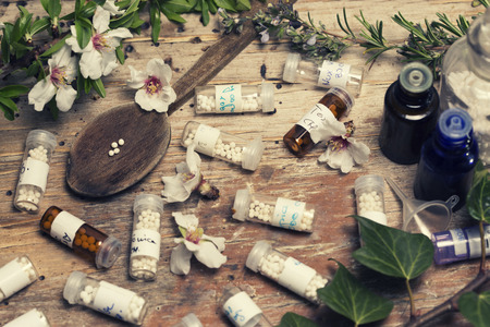 bottles with homeopathy globules and spoon, flowers and ivyのeditorial素材