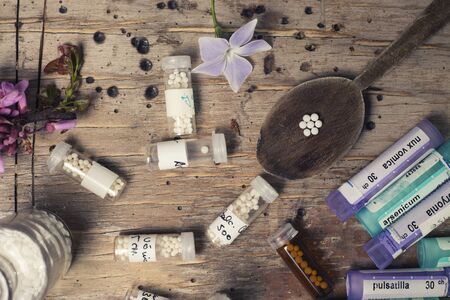 bottles with homeopathy globules and spoon, decorated with flowerのeditorial素材