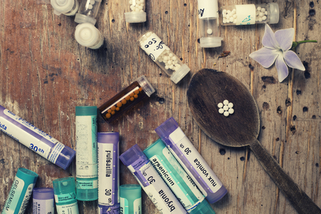 bottles with homeopathy globules and spoon, decorated with flowerのeditorial素材