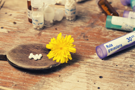 bottles with homeopathy globules and spoon, decorated with flower yellowのeditorial素材