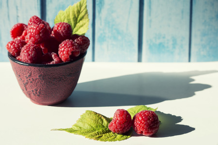 Raspberries bowl with copy space on blue wooden background.