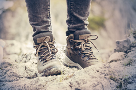 Girls hiking boots. Mountain landscape. Dirty earth and stonesの写真素材