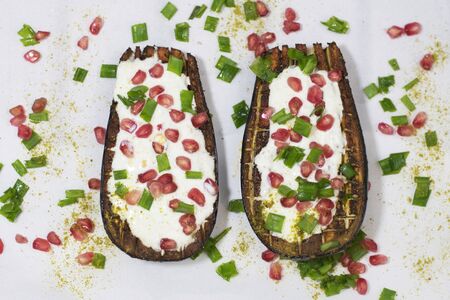 Baked eggplants with garlic yoghurt sauce and pomegranate. White background. Top viewの写真素材