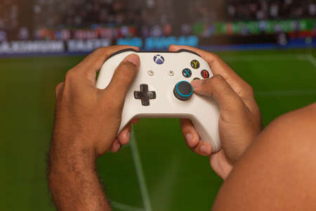 man holding on a xbox gamepad in front of game screenのeditorial素材