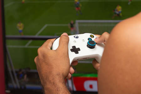 man holding on a xbox gamepad in front of game screenのeditorial素材