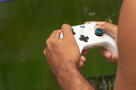 man holding on a xbox gamepad in front of game screenのeditorial素材