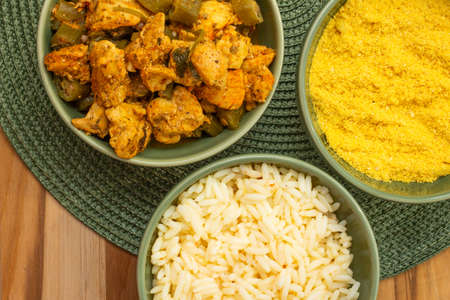 top view of delicious brazilian meal with bowls full of piece of chicken, rice and "farofa" on the wood backgroundの写真素材