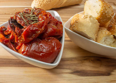 Bowl Full Of Dryied Tomato A Surrounding By Bread Covered With Sesameの写真素材