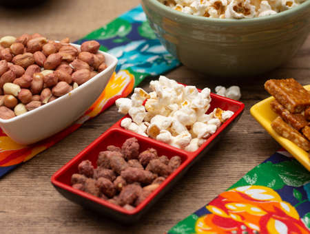 several bowls with popcorn and sweet and salted peanuts on the tableの写真素材