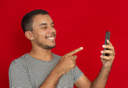 a man using a cellphone with a red backgroundの写真素材