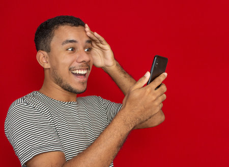 a man using a cellphone with a red backgroundの写真素材