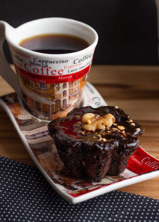 a cup of coffee and a chocolate candie under the wood table with a black backgroundの写真素材