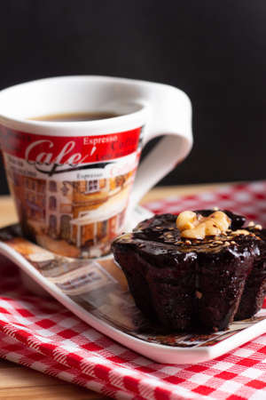 a cup of coffee and a chocolate candie under the wood table with a black backgroundの写真素材