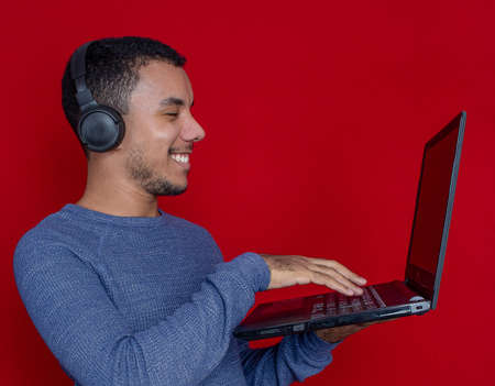 man smiling listening music and holding laptopの写真素材