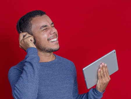 man smiling listening music and holding tabletの写真素材