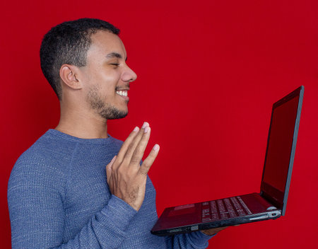 man smiling listening and holding on a laptopの写真素材