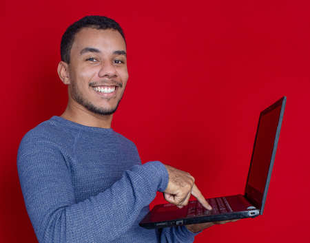 man smiling listening and holding on a laptopの写真素材