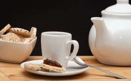 a cup of coffee surrounded by a bowl full of rice cookies and a coffee potの写真素材