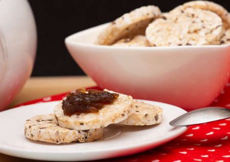 close up of a plate with vegan rice cookies with jelly on the top beside a bowl full of rice cookiesの写真素材