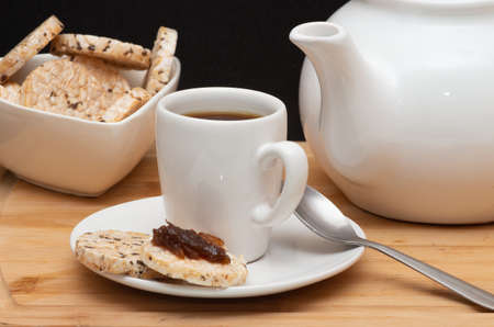 a cup of coffee beside a rice vegan cookies surounded by a coffee pot and a bowl full of cookiesの写真素材