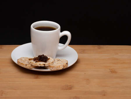 cup of coffee beside rice vegan cookies with jelly on the top under the wood tableの写真素材