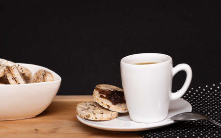 a cup of coffee beside a rice vegan cookies with jelly on the top and a bowl full of rice cookiesの写真素材