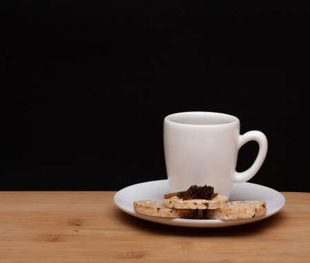 cup of coffee beside rice vegan cookies with jelly on the top under the wood tableの写真素材