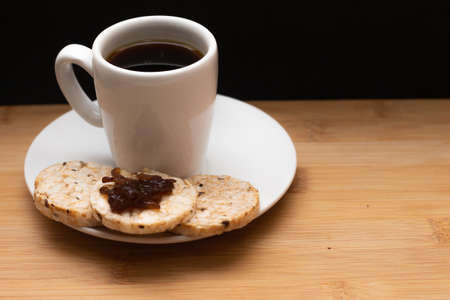 cup of coffee beside rice vegan cookies with jelly on the top under the wood tableの写真素材