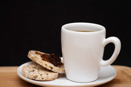 a cup of coffee beside a rice vegan cookies with jelly on the topの写真素材