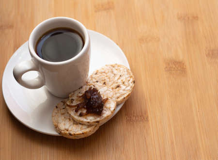 cup of coffee beside rice vegan cookies with jelly on the top under the wood tableの写真素材