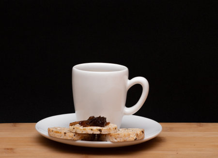 cup of coffee beside rice vegan cookies with jelly on the top under the wood tableの写真素材