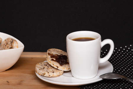 a cup of coffee beside a rice vegan cookies with jelly on the top and a bowl full of rice cookiesの写真素材