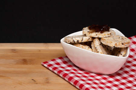 a bowl full of rice vegan cookies with jelly on the top under the fabric in a wood tableの写真素材