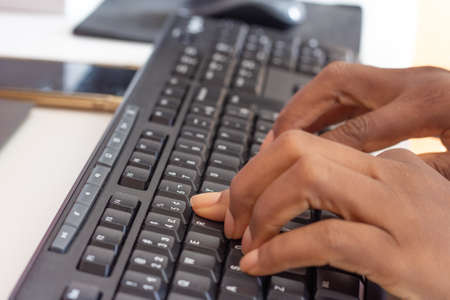 person typing on keyboard in front of a tablet and cellphoneの写真素材