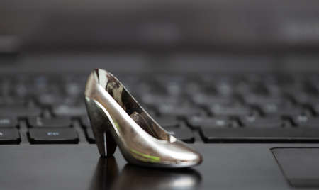 A keyboard from a computer with a small female heel shoe on topの写真素材