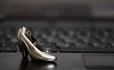 A keyboard from a computer with a small female heel shoe on topの写真素材