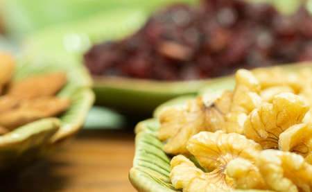 three green bowls full of cranberries, almonds and nuts on the wooden tableの写真素材