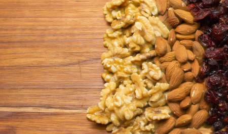 top view of cranberries, walnuts and almonds on a wooden tableの写真素材