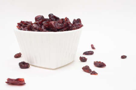 small white bowl full of cranberries on the white backgroundの写真素材