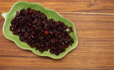 top view of green bowl full of cranberries on the wooden tableの写真素材