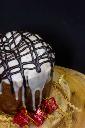 Panettone on a wooden table with a black background surrounded by Christmas ornamentsの写真素材