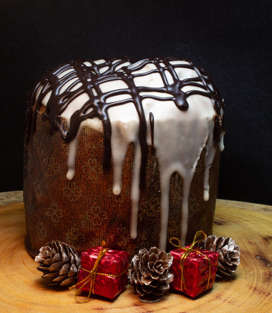 Panettone on a wooden table with a black background surrounded by Christmas ornamentsの写真素材