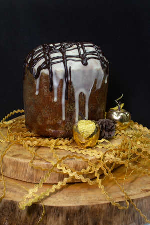 Panettone on a wooden table with a black background surrounded by Christmas ornamentsの写真素材