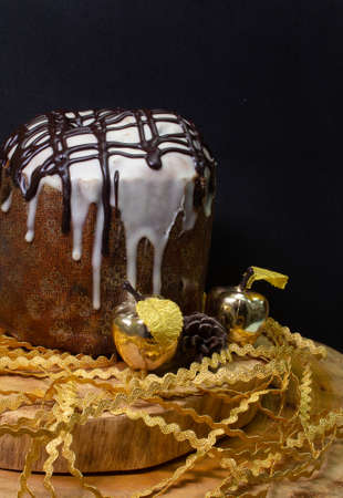 Panettone on a wooden table with a black background surrounded by Christmas ornamentsの写真素材