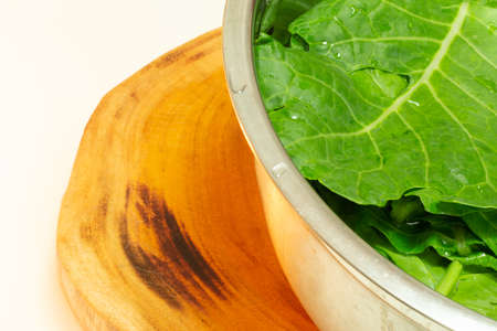 Cabbage leaves inside a bowl of stainless steel on a wood background