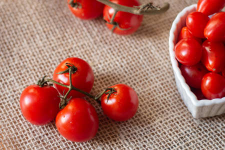 tomatoes inside a white bowl and on to a straw tableの写真素材