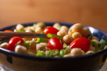 chickpeas with leaves, olives and tomatoes in a blue bowlの写真素材