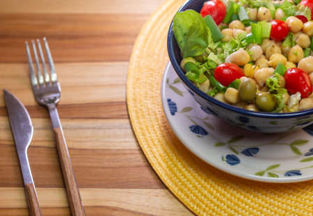 chickpeas with leaves, olives and tomatoes in a blue bowl on the tableの写真素材